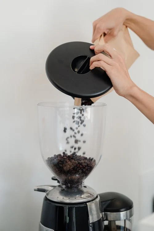 Coffee beans being poured into a grinder
