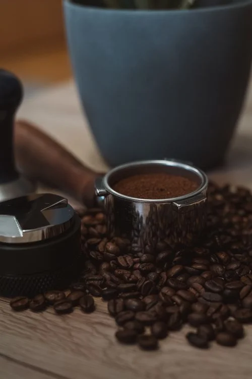 Espresso tools with a portafilter, tamper, and coffee beans